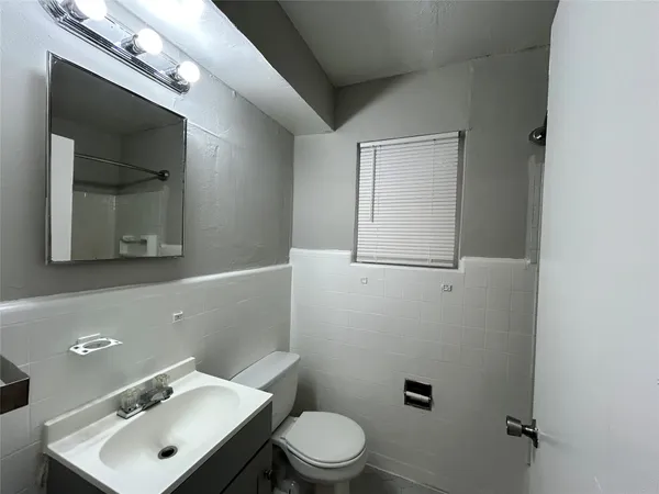 a bathroom with a toilet sink vanity and mirror