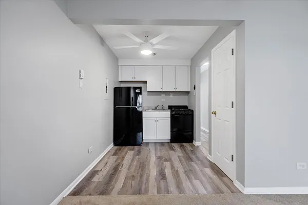 a view of a kitchen with refrigerator and wooden floor