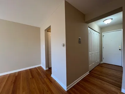 a view of an empty room with wooden floor and a bathroom