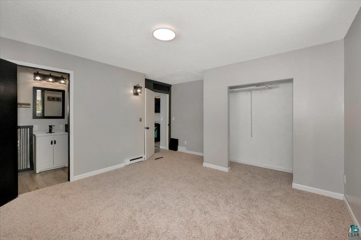 1146 Two Harbors Road Two Harbors, MN 55616 - Photo 12 of 39 Unfurnished bedroom featuring light carpet, a textured ceiling, a closet, and baseboard heating