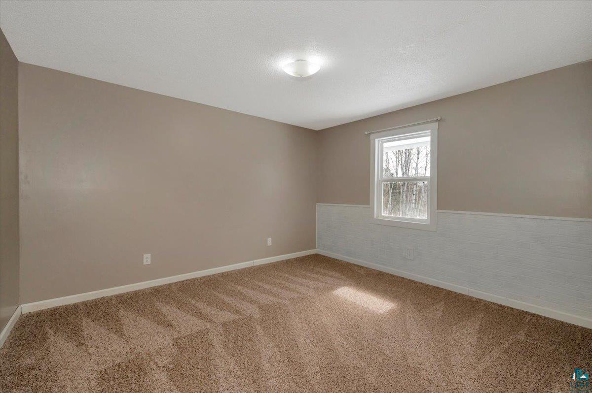 1146 Two Harbors Road Two Harbors, MN 55616 - Photo 17 of 39 Spare room with carpet flooring, a wainscoted wall, and a textured ceiling