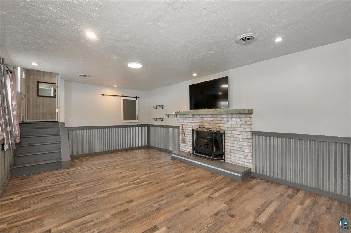 1146 Two Harbors Road Two Harbors, MN 55616 - Photo 20 of 39 Unfurnished living room with wainscoting, dark wood-style flooring, a textured ceiling, and a brick fireplace