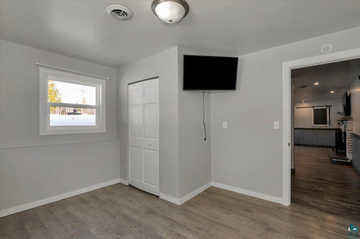 1146 Two Harbors Road Two Harbors, MN 55616 - Photo 21 of 39 Unfurnished bedroom with wood finished floors, a closet, radiator, and a fireplace with raised hearth