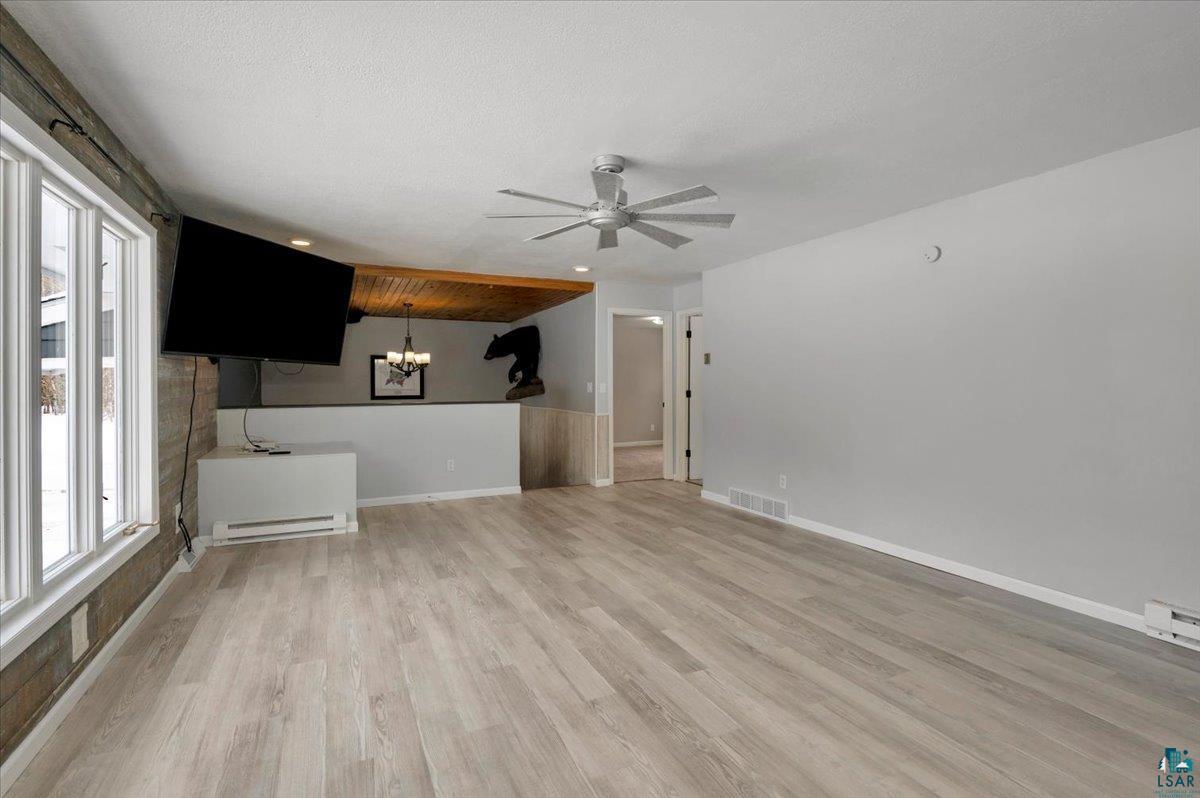 1146 Two Harbors Road Two Harbors, MN 55616 - Photo 5 of 39 Unfurnished living room featuring light wood-style flooring, ceiling fan, suspended lighting, and a baseboard heating unit