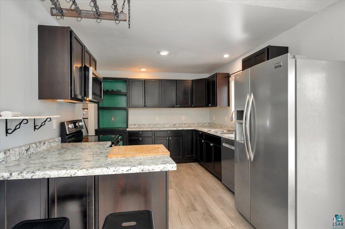 1146 Two Harbors Road Two Harbors, MN 55616 - Photo 9 of 39 Kitchen with stainless steel appliances, a peninsula, light wood finished floors, a breakfast bar area, and open shelves