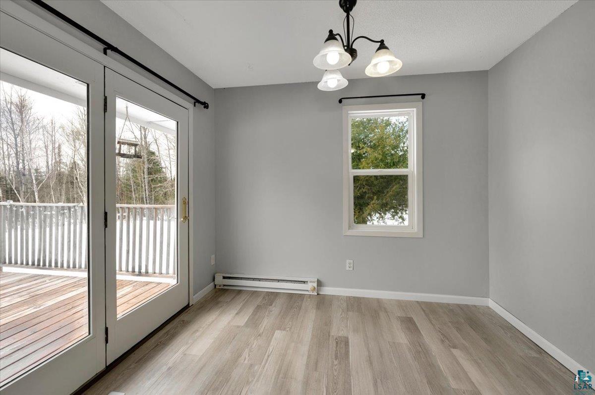 1146 Two Harbors Road Two Harbors, MN 55616 - Photo 10 of 39 Unfurnished dining area featuring suspended lighting, light wood-style floors, and baseboard heating