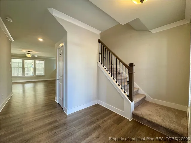 a view of an empty room with wooden floor and a ceiling fan