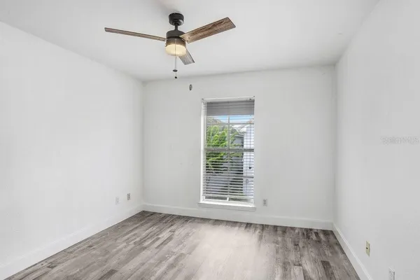 an empty room with a window and a ceiling fan
