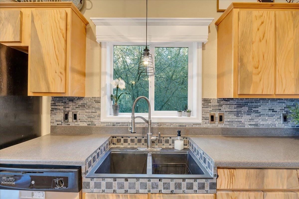 22389 Parrotts Ferry Road Columbia, CA 95310 - Photo 46 of 60 Kitchen with light brown cabinets, dishwashing machine, hanging light fixtures, and backsplash