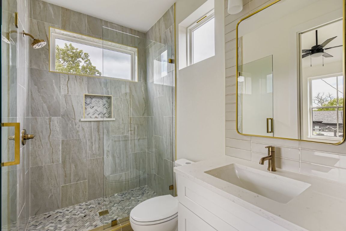 4712 South Forest Drive Austin, TX 78745 - Photo 20 of 27 a bathroom with a sink a toilet a glass door shower and a mirror