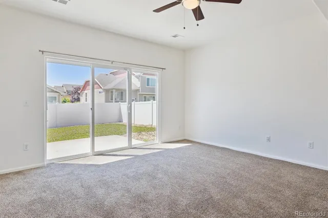 an empty room with ceiling fan and window