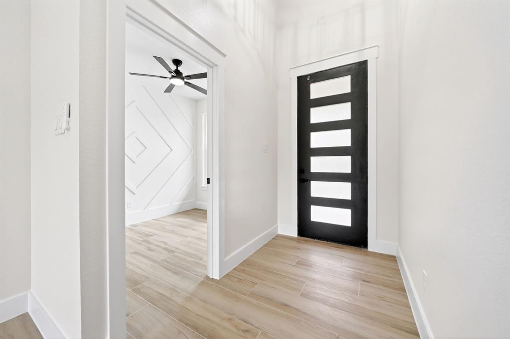 120 Springwood Road Enchanted Oaks, TX 75156 - Photo 4 of 37 Entryway featuring a modern black door with frosted glass panels, wood-finish flooring, and white baseboards