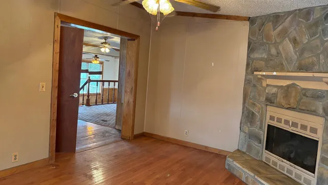 a view of an empty room with wooden floor a fireplace and a window