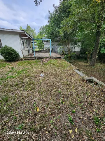 a backyard of a house with plants and large tree