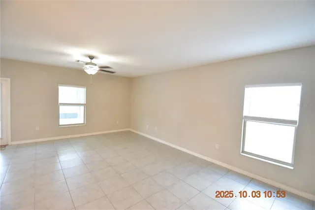 an empty room with windows and chandelier fan