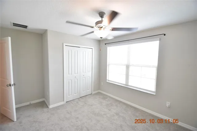 an empty room with windows and fan