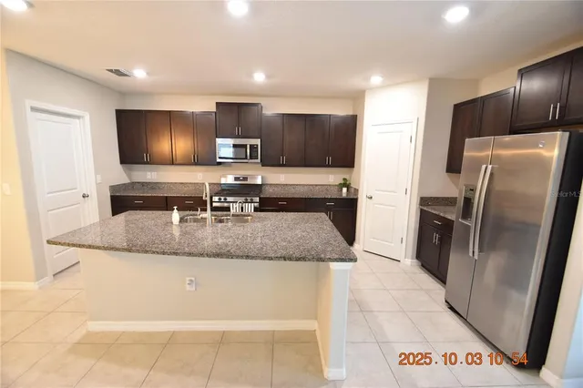 a kitchen with stainless steel appliances granite countertop a refrigerator a sink a stove a microwave and island