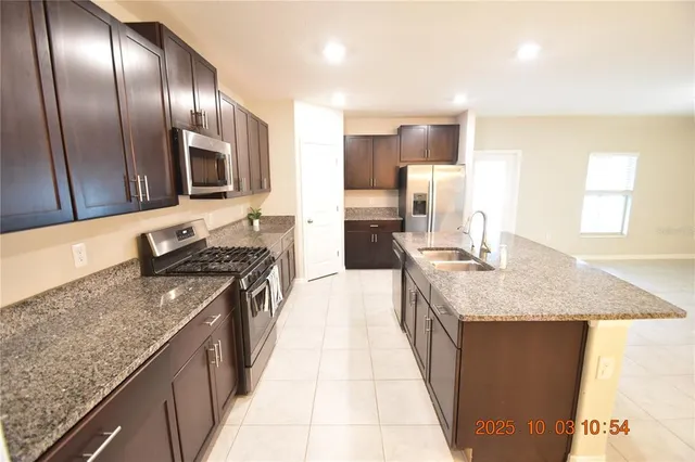 a large kitchen with granite countertop counter top space a sink stainless steel appliances and cabinets