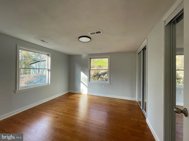 a view of an empty room with wooden floor and a window