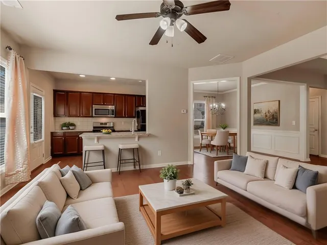 a living room with furniture kitchen view and a wooden floor