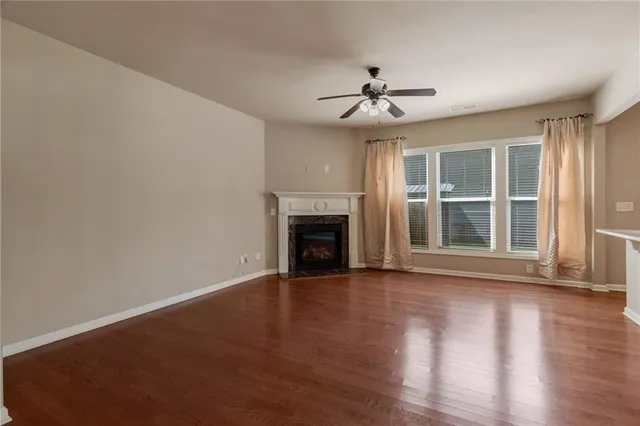 a view of an empty room with wooden floor fireplace and a window