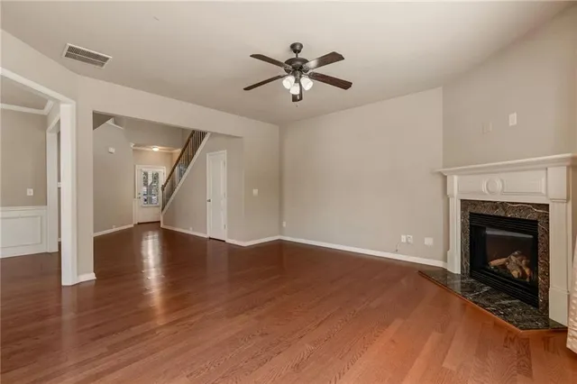 a view of an empty room with wooden floor fireplace and a window