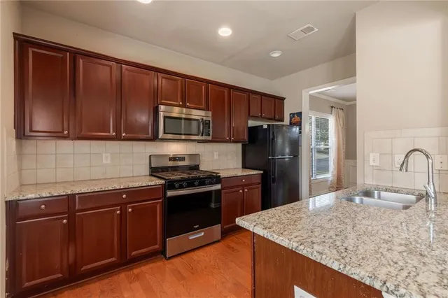 a kitchen with stainless steel appliances granite countertop wooden cabinets a stove top oven a sink and dishwasher
