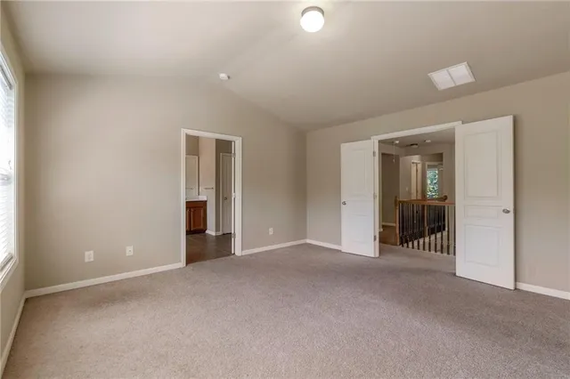 a view of an empty room with closet and a window