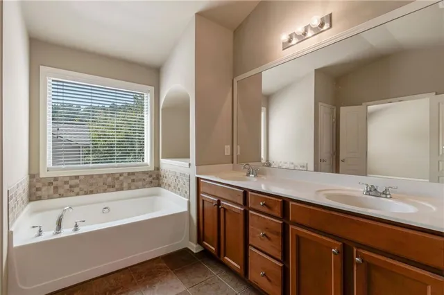a bathroom with a tub a sink double vanity and a mirror