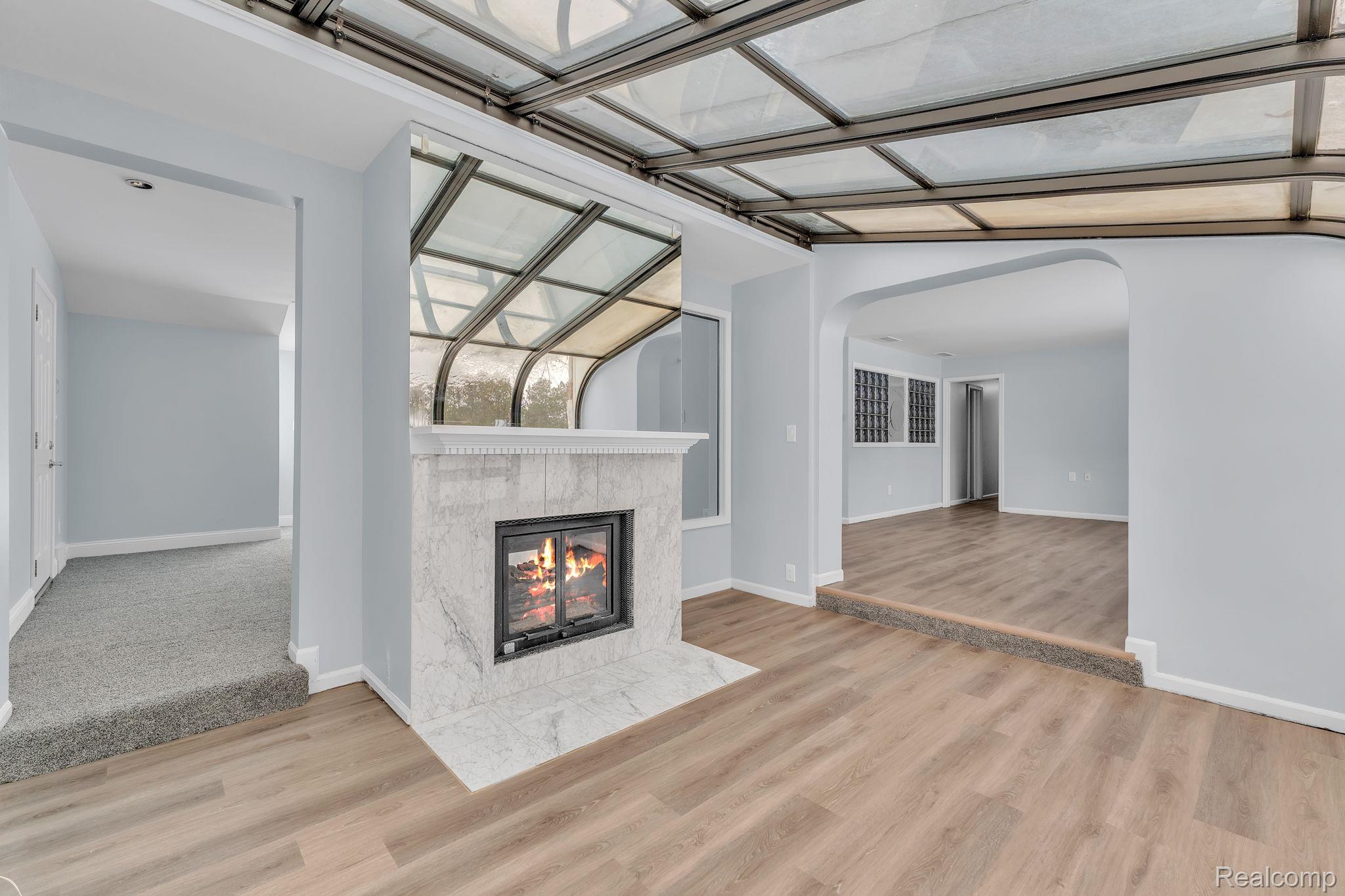 6576 Inkster Road West Bloomfield, MI 48322 - Photo 23 of 62 Unfurnished living room with arched walkways, a tile fireplace, and light wood-style flooring