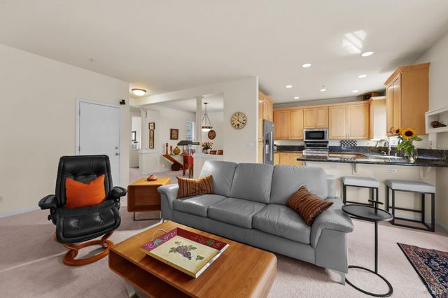 a living room with furniture wooden floor and kitchen view