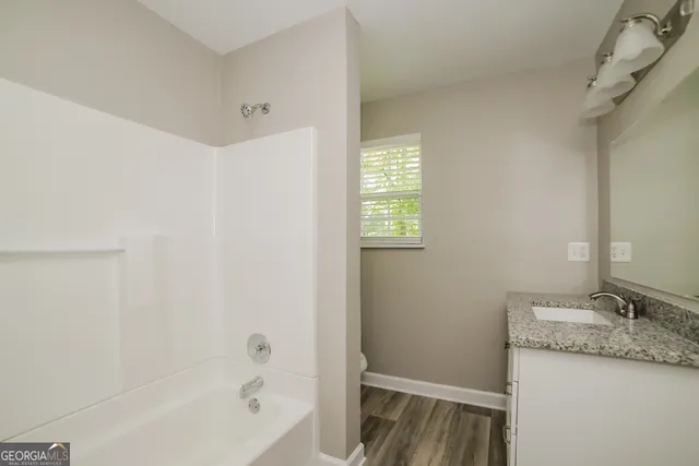 a bathroom with a granite countertop sink and a bathtub