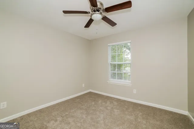 an empty room with a window and a fan