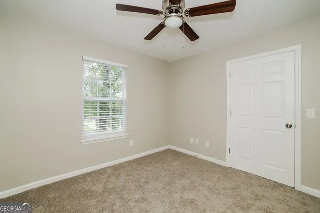 an empty room with a window and a fan