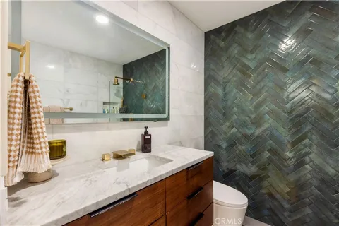 a bathroom with a granite countertop sink a toilet and a mirror