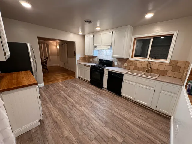 a kitchen with stainless steel appliances granite countertop a sink dishwasher stove and refrigerator with wooden floor