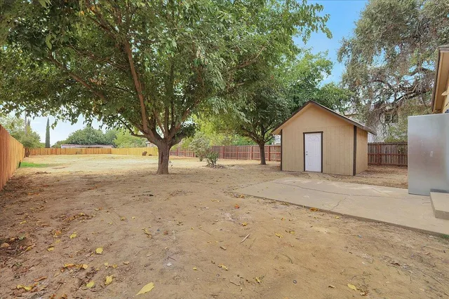a view of a house with a yard and large tree