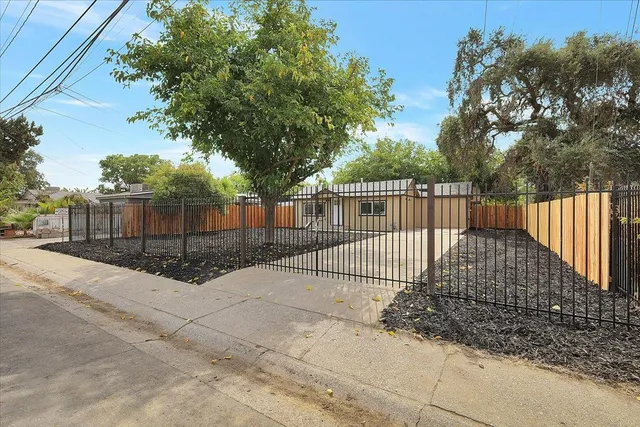 a view of street with a small yard and wooden fence