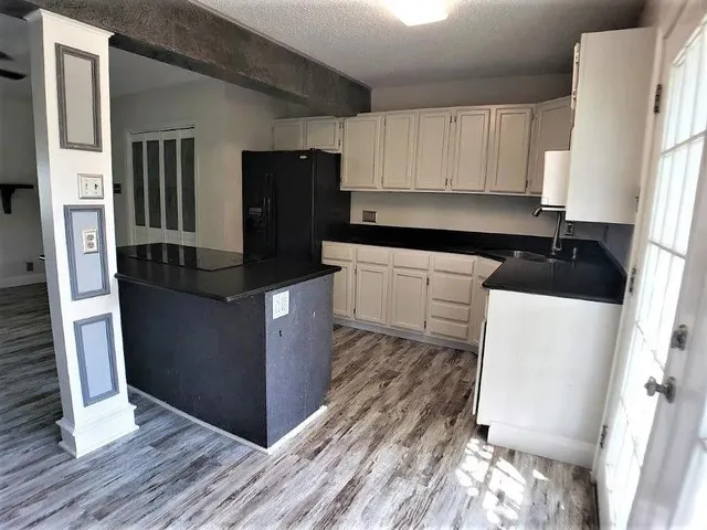 a kitchen with granite countertop a refrigerator and a stove top oven