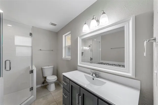 a bathroom with a sink a toilet a mirror and shower