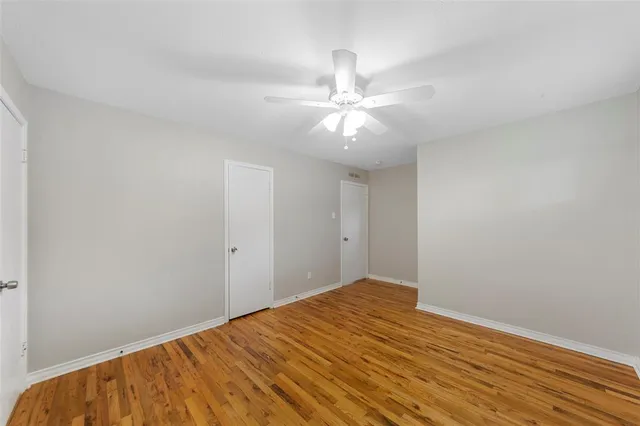 a view of a big room with wooden floor and chandelier fan