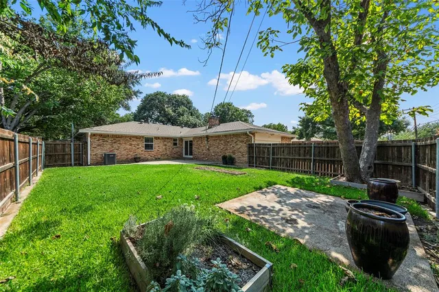 a view of a backyard with couches plants and large tree