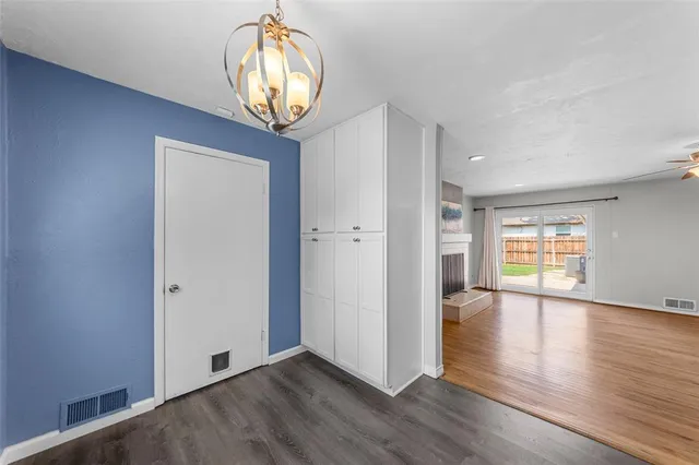 an empty room with wooden floor mirror and windows
