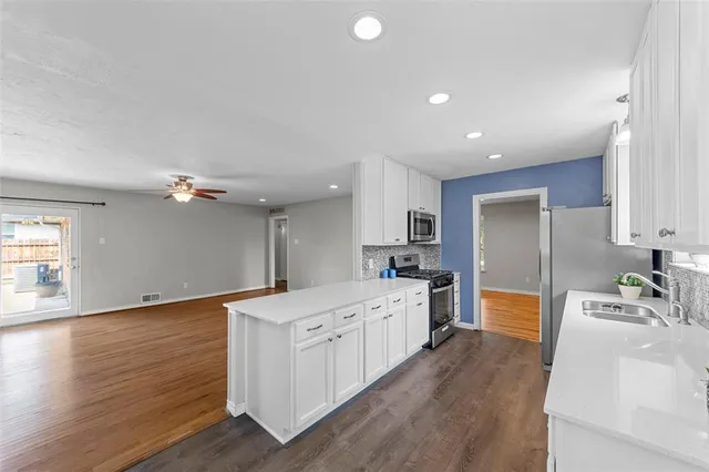 a large kitchen with a lot of counter space and wooden floor