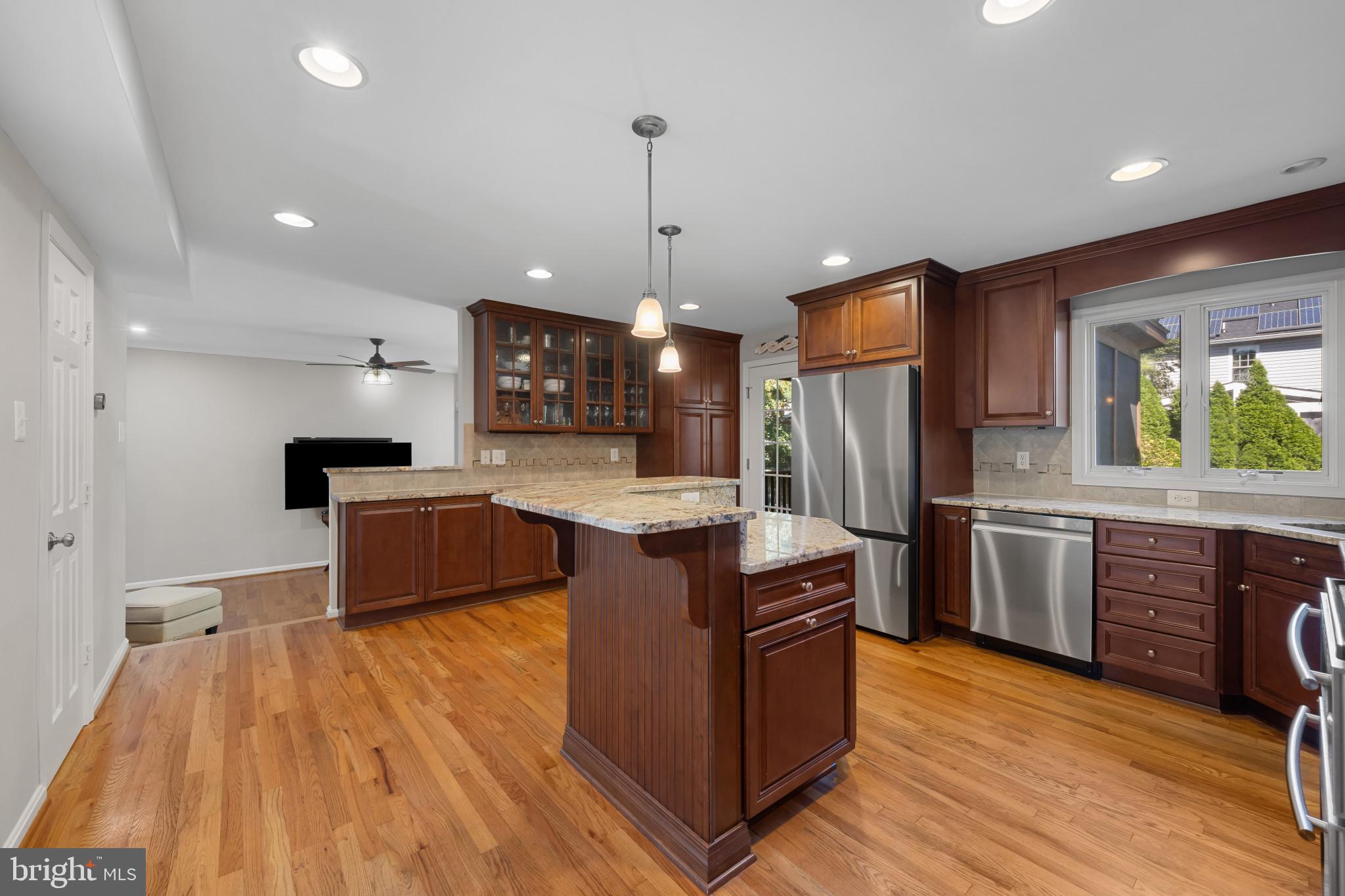 2603 Spartan Road Olney, MD 20832 - Photo 12 of 62 a kitchen with stainless steel appliances kitchen island granite countertop a stove top oven a sink dishwasher a refrigerator and a dining table with wooden floor