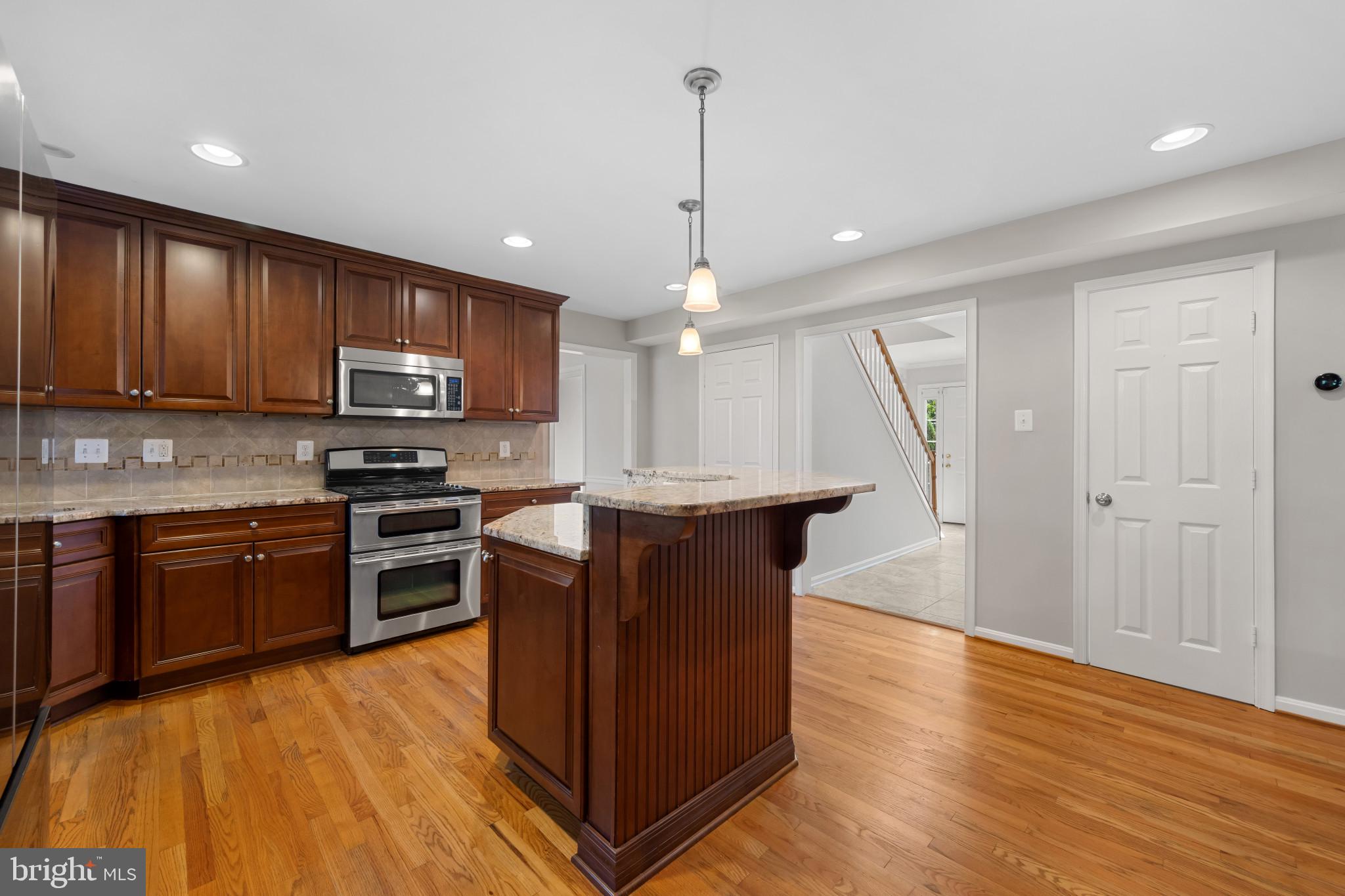 2603 Spartan Road Olney, MD 20832 - Photo 13 of 62 a kitchen with kitchen island granite countertop wooden floors stainless steel appliances a sink