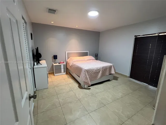 a bedroom with a bed and a refrigerator