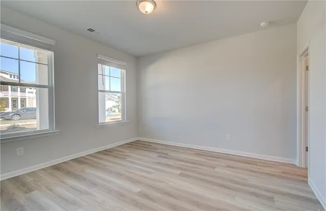 an empty room with wooden floor and windows
