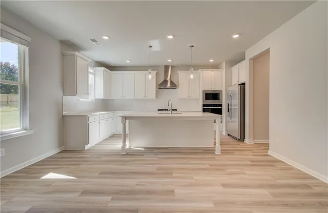 a view of kitchen with kitchen island white cabinets and stainless steel appliances
