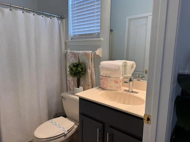 a bathroom with a sink a toilet and shower curtain